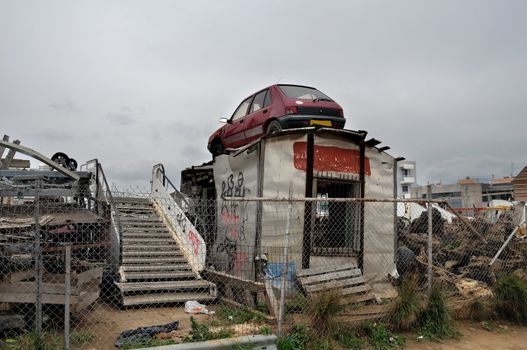 Rusty car and scrap metal at a junkyard.