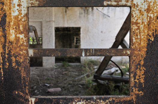 Rusty industrial door with chipped paint and view to abandoned warehouse interior.