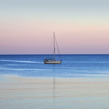 Sailboat reflections on sea water. Sunset sea and sky horizon.