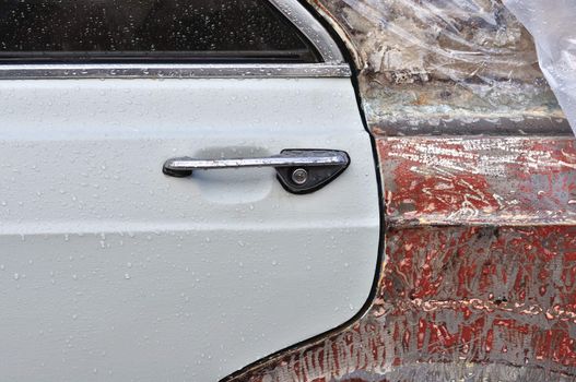 Vintage car window and scraped metal door with raindrops. Background texture.