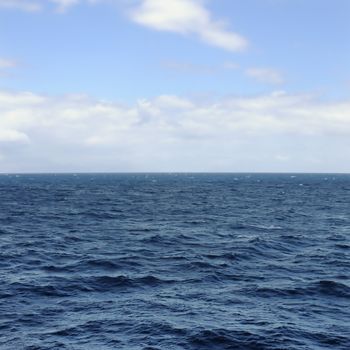 Deep open sea water and blue sky horizon.