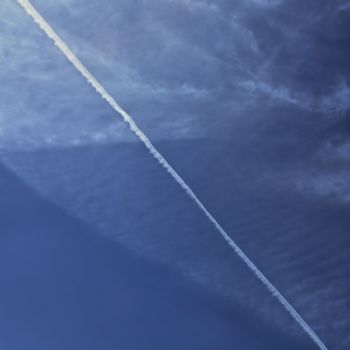 Airplane smoke trail on cloudy sky. Abstract background.