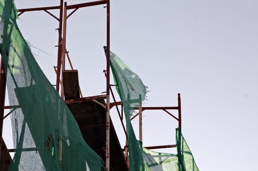 Torn debris netting and scaffold at construction site.