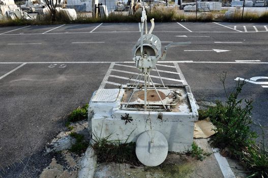Vintage well in empty parking lot. Changing urban landscape and traces of the past.