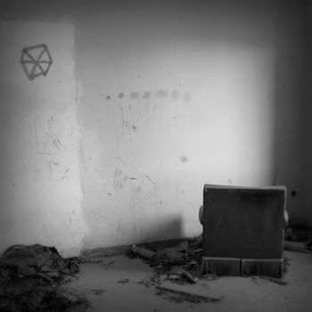 Armchair facing the wall in abandoned house. Black and white.