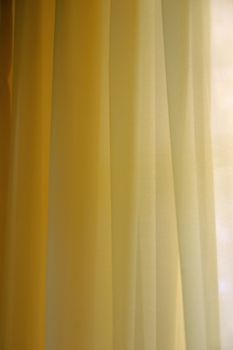 Transparent curtain background texture. Shades of yellow.