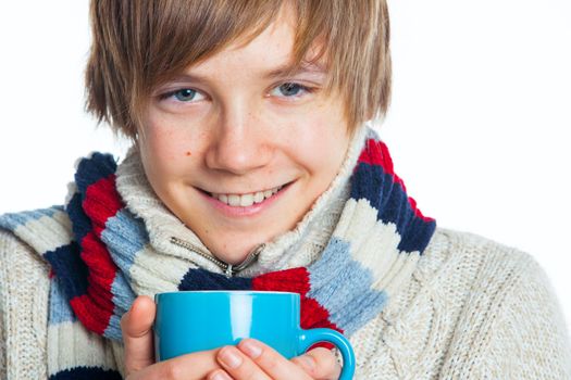 Portrait of young smiling cute frozen teenager in a scarf and with blue cup, isolated on white