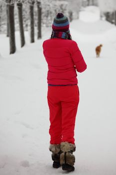 two women walk by winter alley snow trees on background