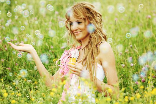  Blonde starts soap bubbles in a green field