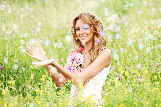  Blonde starts soap bubbles in a green field