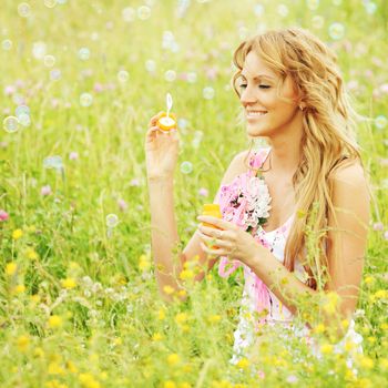  Blonde starts soap bubbles in a green field