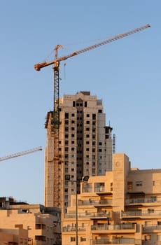 Lifting crane and building under construction at sunset