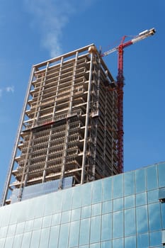 Lifting crane and high building under construction 