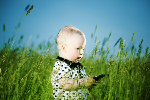little boy in green grass call by phone