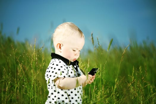 little boy in green grass call by phone