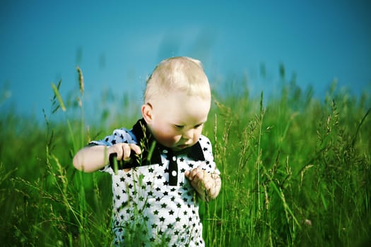 little boy in green grass call by phone