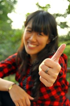 Asian woman thumbs up outdoor