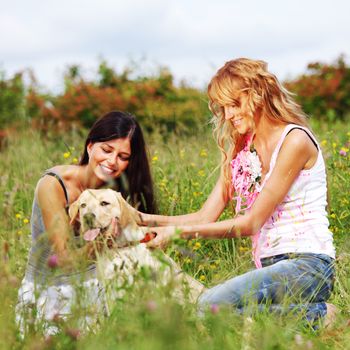 girlfriends and dog in green grass field