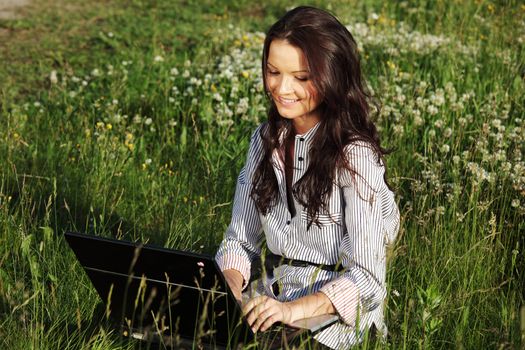 girl with laptop on green grass