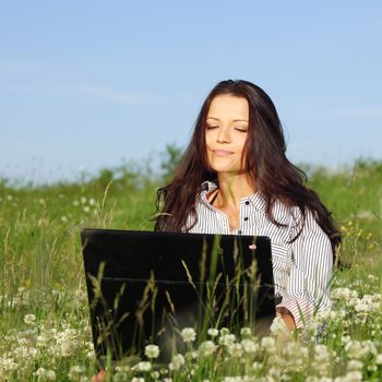 girl with laptop on green grass