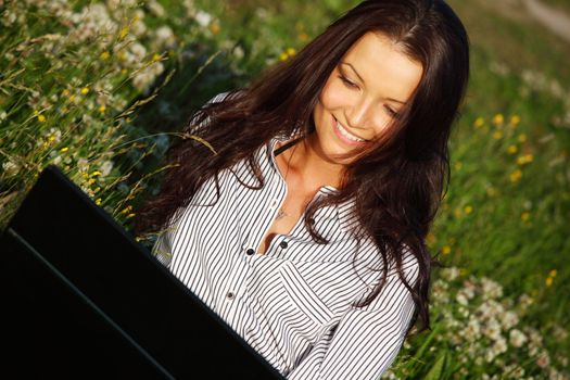 girl with laptop on green grass