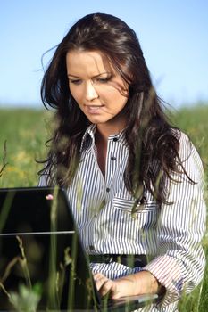 girl with laptop on green grass