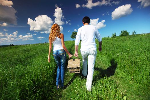 man and woman walk on picnic in green grass