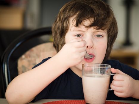 Boy drinking a hot chocolate with a spoon