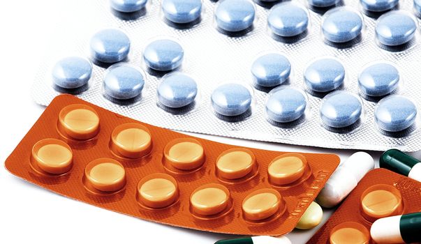 Pills of many shapes and colors grouped together.
