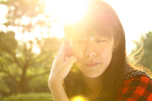 Asian woman thinking under sunshine