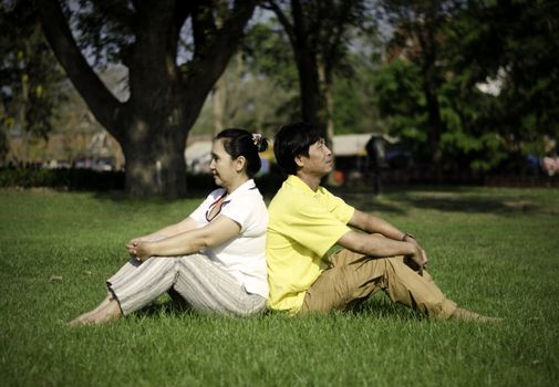 Portrait of beautiful couple sitting on ground in park relaxing 
