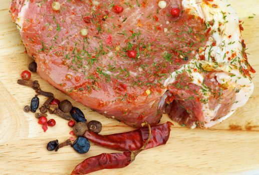 Marinated Raw Pork with Herbs, Greens and Spices closeup on Wooden Cutting Board