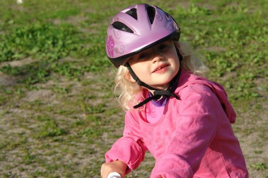 Cute little girl with a helmet riding a bike