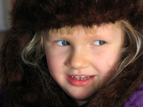 Little cute girl with winter fur hat out in the snow