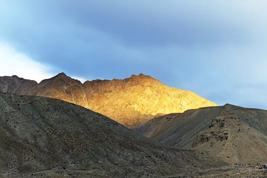 top of the mountain lit by the setting sun in the background