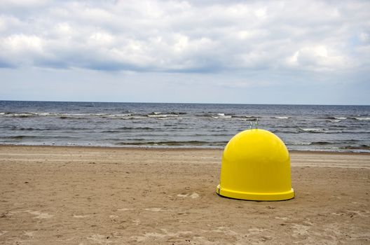 yellow plastic garbage box on beach sand and sea