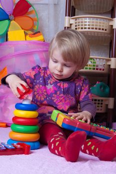 Baby girl collecting pyramid in playing-room