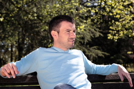 handsome man resting on a bench in a park