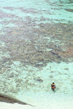 Young man   over coral reef in transparent tropical sea