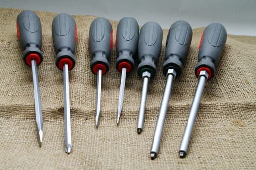 A screwdriver set on a burlap background