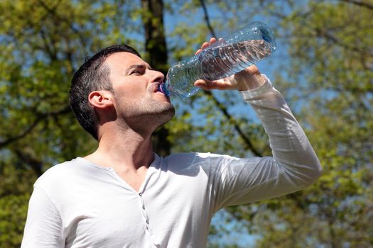 attractive man drinking water in a park