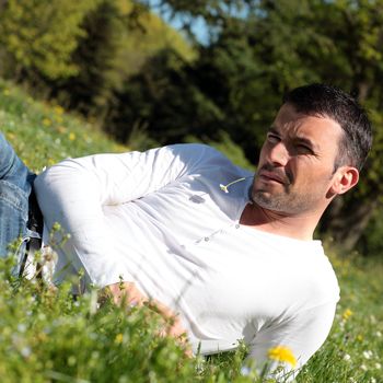 handsome man with daisy in a park