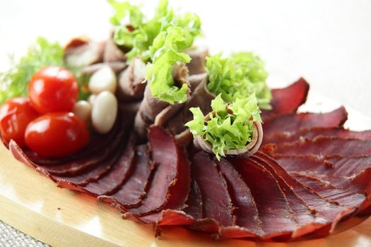 sliced bacon with salad and tomatoes on wooden plate