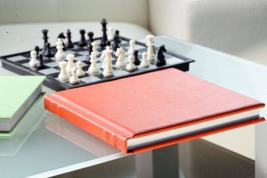 orange leather book on bright background and chess