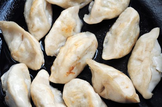 Chinese dumplings being fired in an iron pan