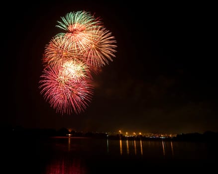 Green Pink and Orange Fireworks at lake on King Birthday Festival and Holiday in Thailand.