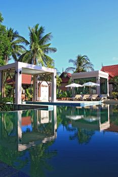 Reflection of Pool in Tropical Garden and Spa Section with beach chair, Vertical