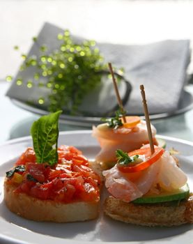 Canape juicy tomatoes shrimp on fresh bread pesto as topping (selective focus at front)