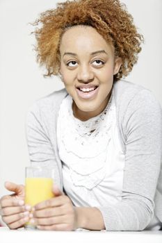 Attractive black woman  relaxing in living room with a glass of juice