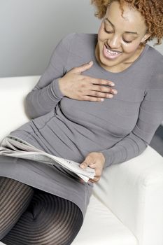 Beautiful young woman reading a newspaper at home